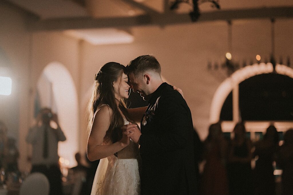 Bride and Groom press their foreheads together during their first dance at wedding reception. 