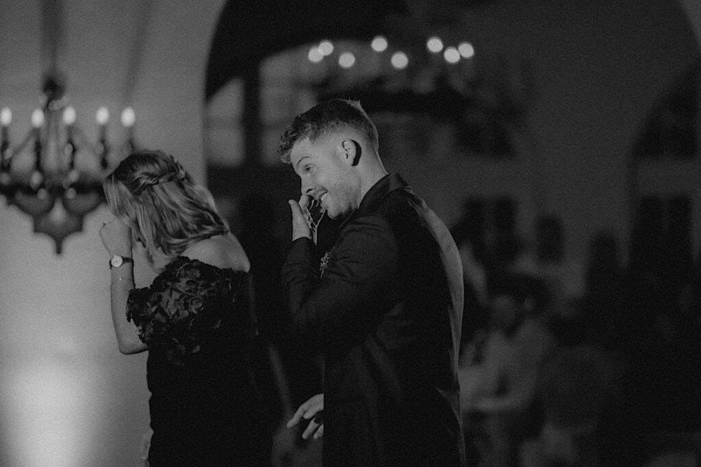 Groom walks with his mom onto the dance floor as they both pat their teary eyes. 