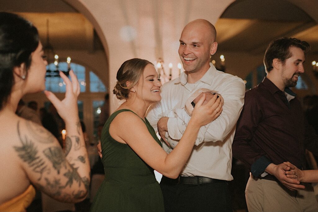 Wedding guests craddle their baby with headphones on during wedding reception at Ravisloe Country Club. 