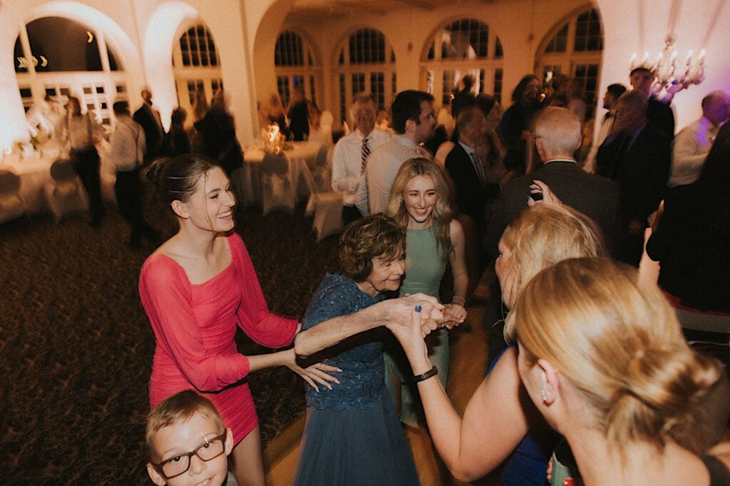 Wedding Guest women help grandmother in a blue dress onto the dance floor during reception at Ravisloe Country Club. 