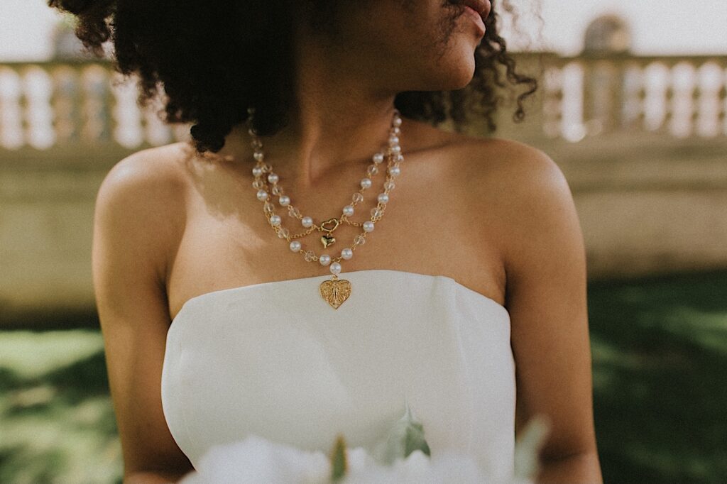 Springfield elopement photographer captures Bride's layered pearl necklaces above her strapless white elopement dress. 