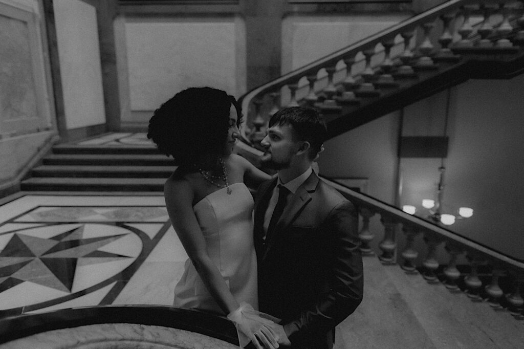 Bride and groom stand on the top of a staircase staring into each other's eyes during romantic elopement portraits. 