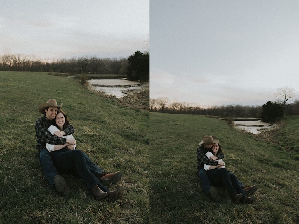 Man with cowboy hat sits and hugs girl on grass while looking at each other for cozy engagement photos in Springfield, Illinois. 