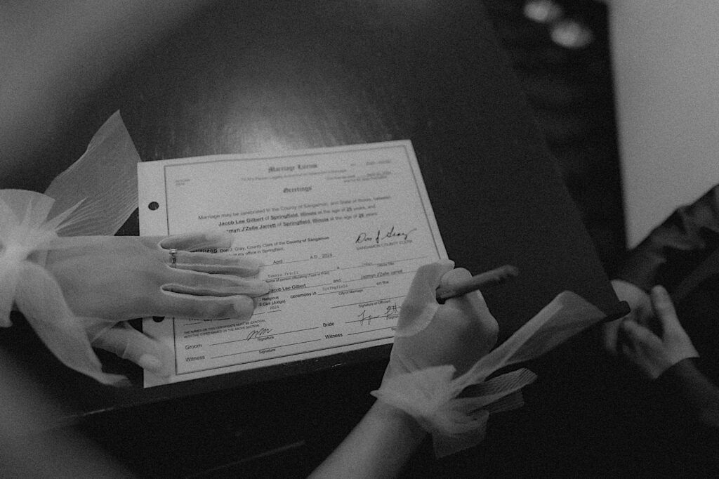 Springfield elopement photographer captures bride's gloved hands signing marriage license. 