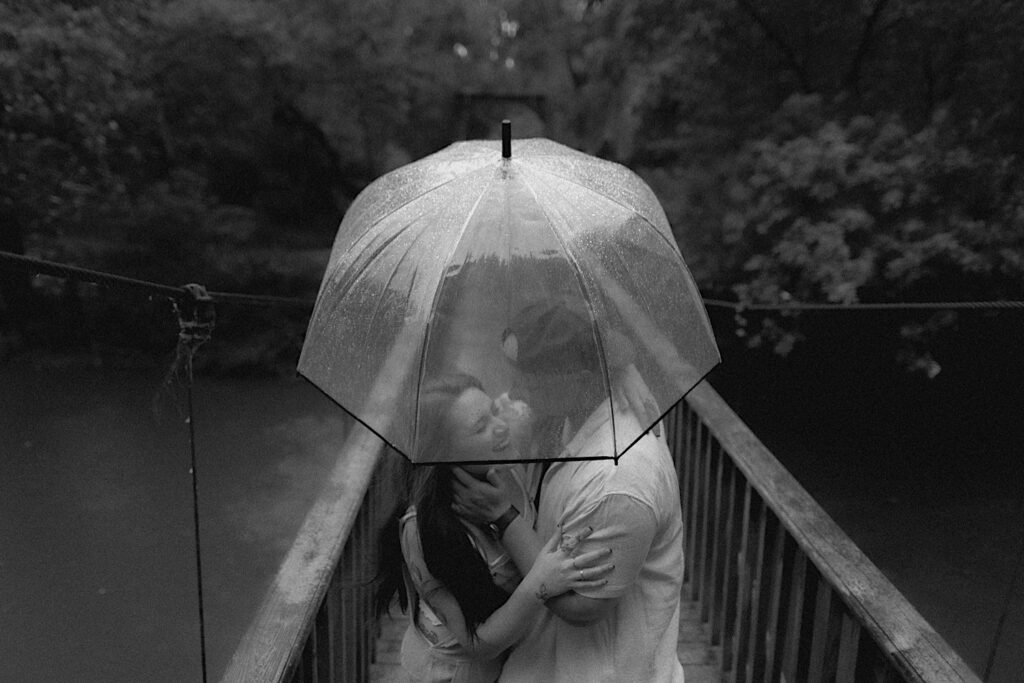 Illinois Engagement photographer captures couple from above as they stand underneath a clear umbrella and laugh embracing. 