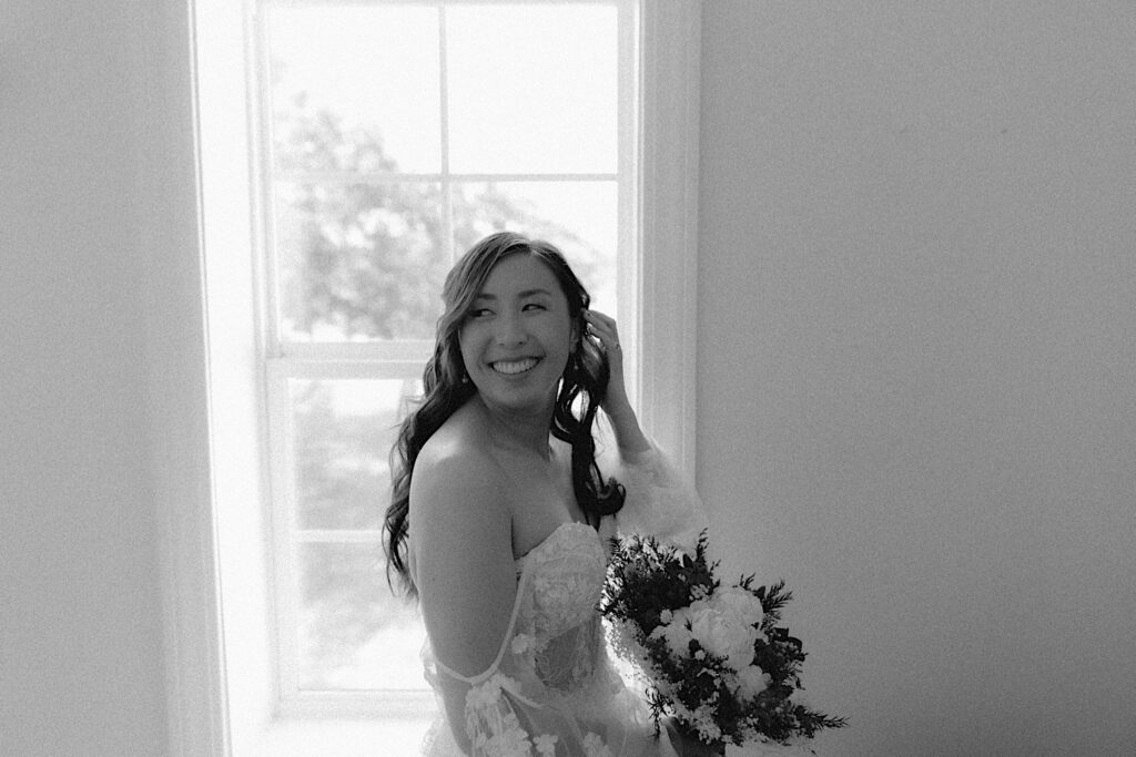 Bride poses in front of window while getting ready for wedding ceremony at Kennedy Estate in Lizton, Indiana. 