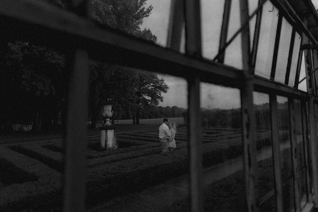 Couple romantically dances within hedge mazes during engagement portrait session at Allerton Park. 