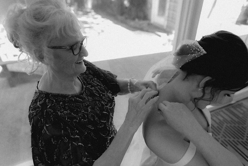 Bride's grandmother puts necklace on bride while getting ready for relaxed wedding ceremony in Central Illinois. 