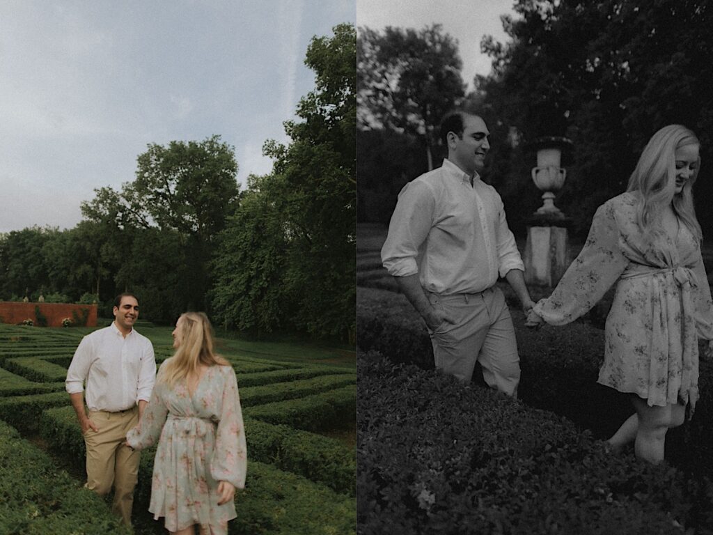 Couple walks hand and hand through hedge maze with beautiful green trees in the background.