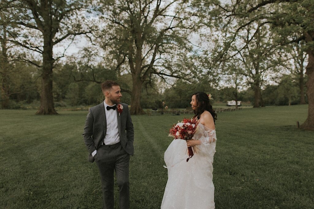 Bride smiles as groom turns to see her for the first time on their wedding day during an intimate first look in the field at Kennedy Estate in Lizton, Indiana before their wedding ceremony. 