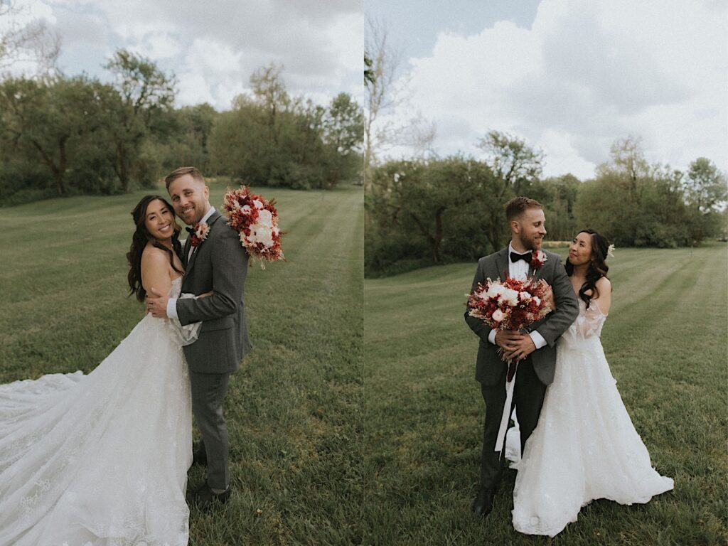 Bride and groom stands in grassy field while they look at each other and the groom hold's the brides large red and white floral bouquet. 