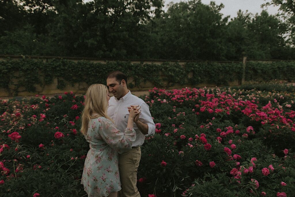 Couple dances within bushes of pink flowers in a garden in Allerton Park. 