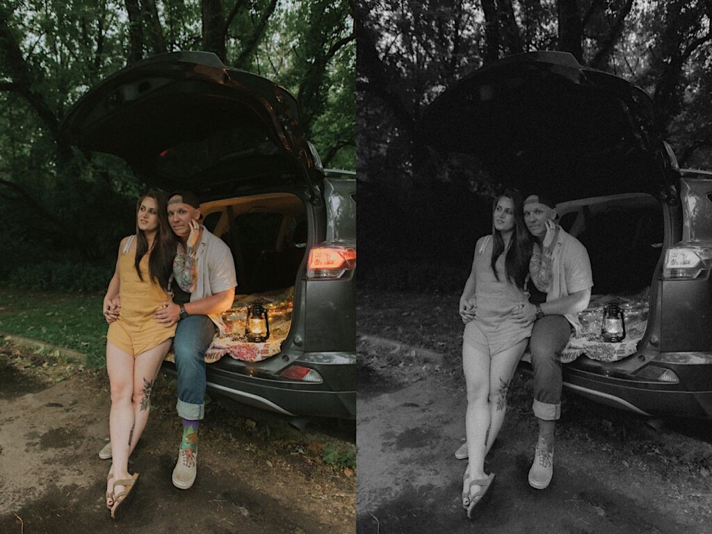 Girl in yellow overalls sits on her fiancé's lap who is wearing a button up and backwards hat. They are sitting on the trunk of their car on a quilt with a lamp next to them. 