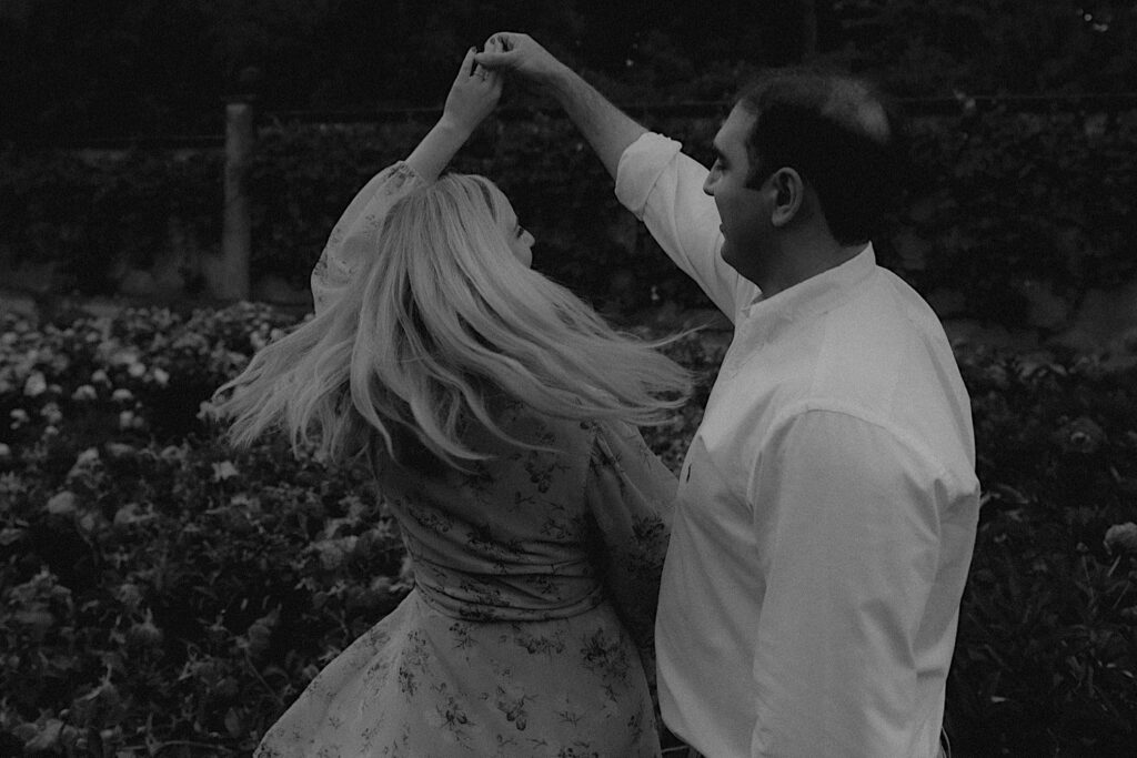 Man spins woman in beautiful garden full of pink flowers in Allerton Park. 