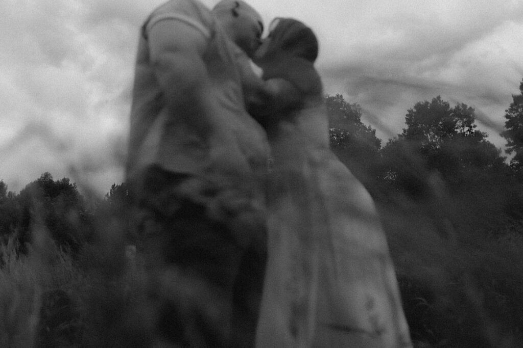 Illinois Wedding photographer captures couple kissing and hugging from underneath them with grass flowing in front of the lens.