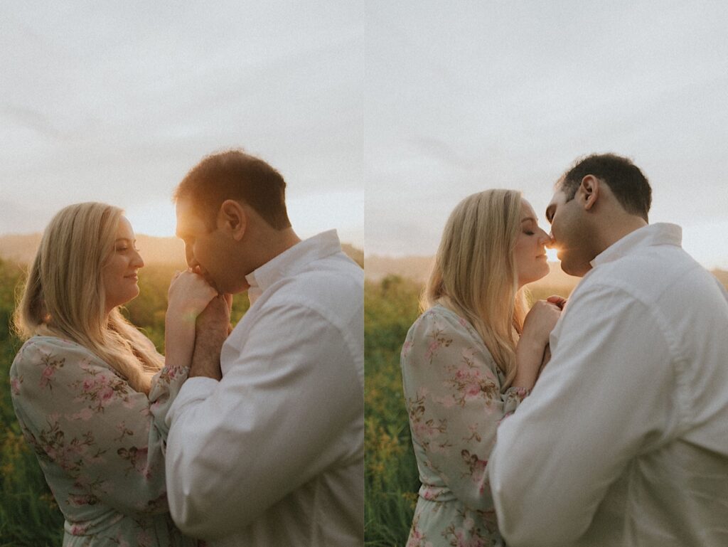 Woman leans towards her fiance while they hold each other's hands in a field with golden hour sun in the background. 