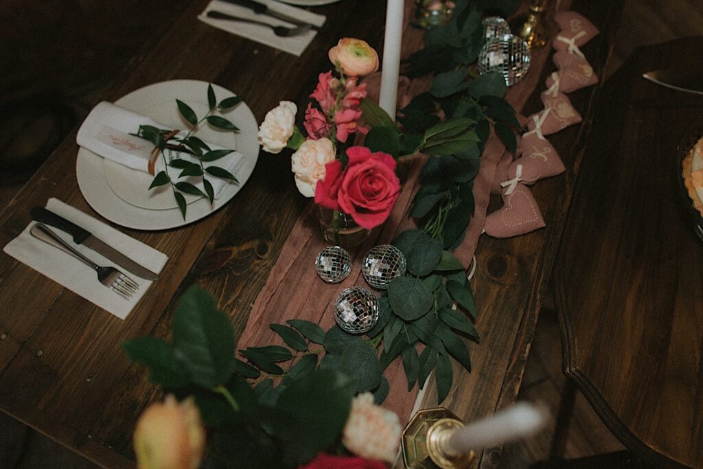 Central Illinois wedding photographer captures table setting with pink and peach roses, mini disco balls, white candles on a mauve table runner. 