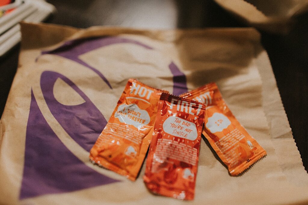 Fire Taco Bell hot sauces sit on-top of a Taco Bell wrapper. 