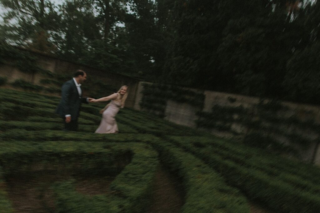 Illinois engagement photographer captures vintage blurry aesthetic portrait of couple running through Allerton Park's Hedge maze. 