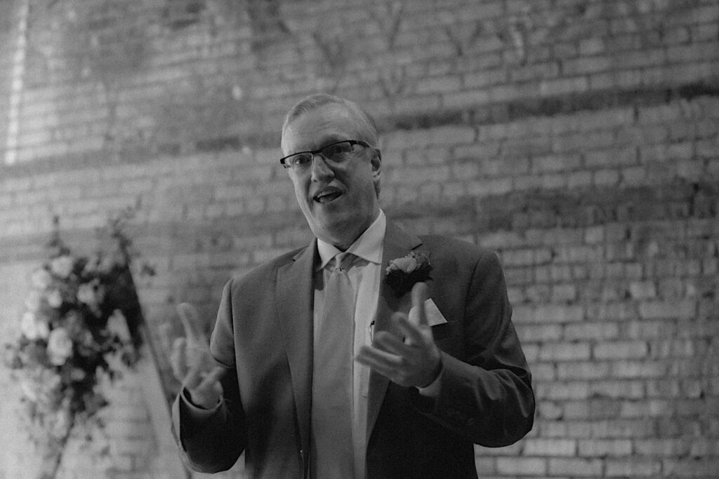 Father of the bride stands up to give a speech during laid back wedding reception at Reality on Monroe in Central Illinois. 