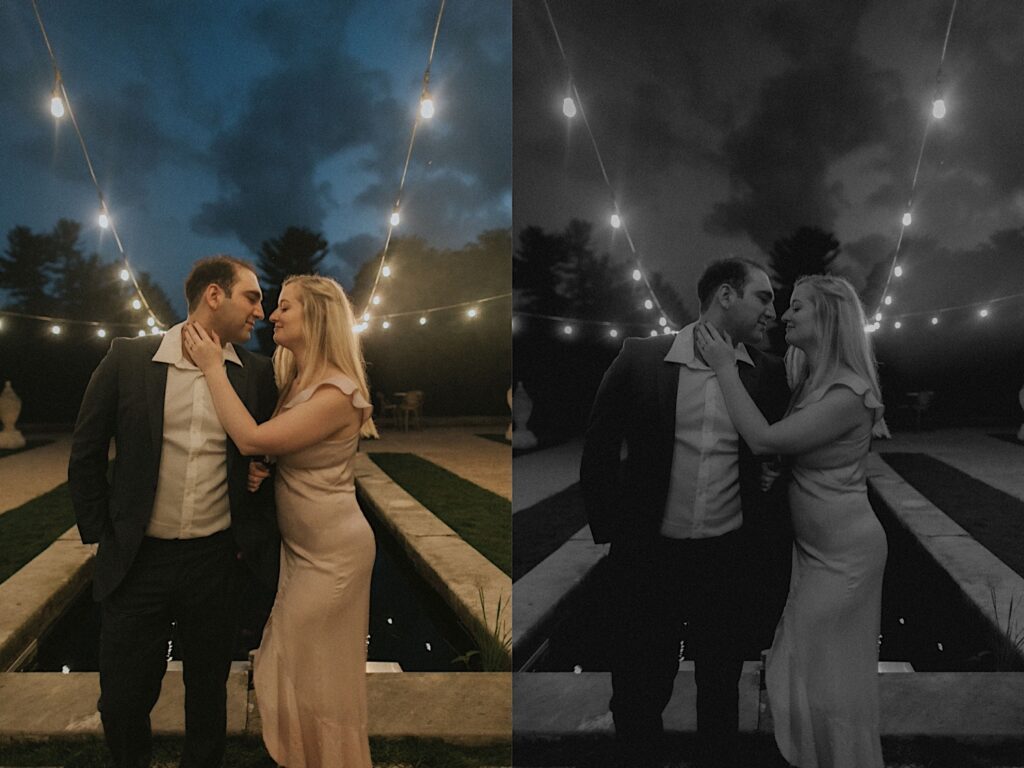 Woman in blush dress places her hand on fiance's neck as they stand in front of pool lit by patio lights. 