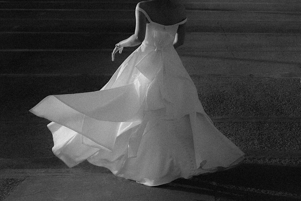 Black and White portrait of the back of the bride as she swings her white dress around. 