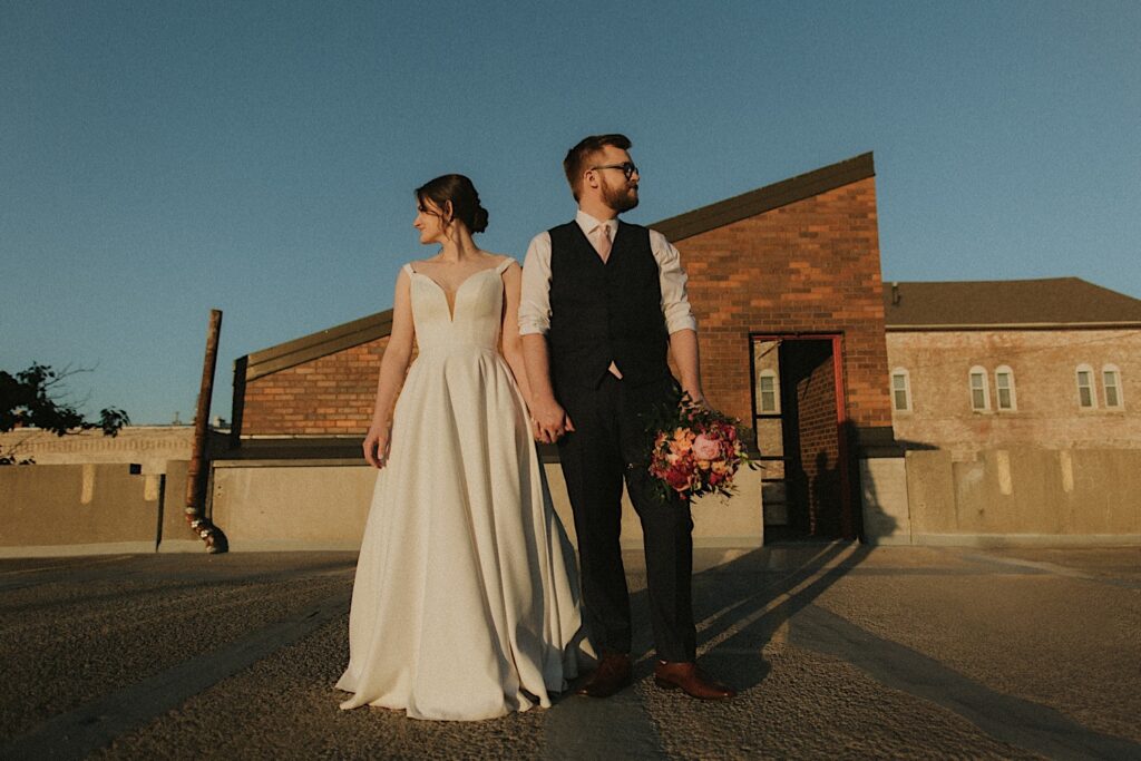 Bride and Groom stand side by side and stare in opposite direction as they stand on the rooftop of Reality on Monroe in Central Illinois. 