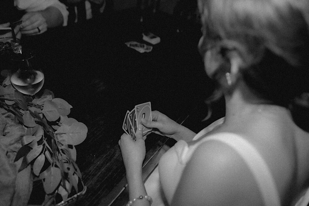 Central Illinois wedding photographer captures the back of the bride holding Uno cards as she plays with the groom. 