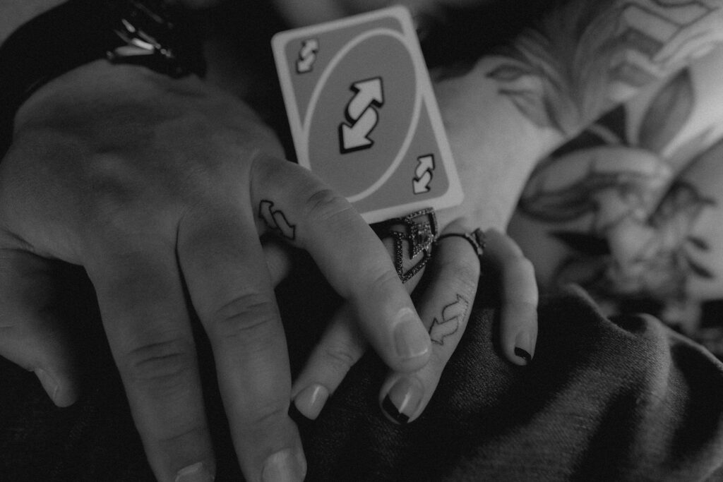 couple poses with ring figures, which have the uno reverse symbol tattooed on their fingers. 