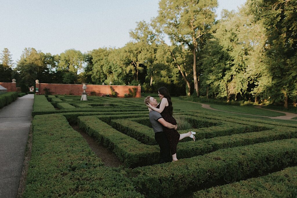 A couple embrace one another while standing in the gardens of Allerton Park in Champaign, Illinois as they have their engagement photos taken