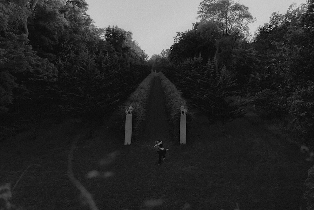 Black and white photo of a couple kissing one another in the gardens of Allerton Park of Champaign, Illinois while having their engagement photos taken