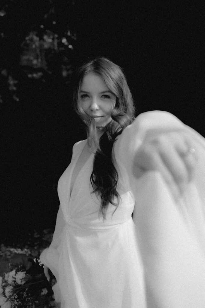 Bride holds her hand to the camera dramatically in a romantic black and white portrait before wedding ceremony in Washington, Illinois. 