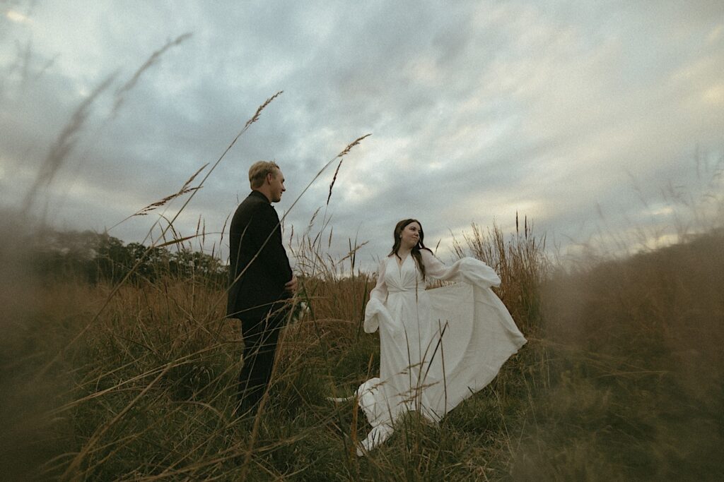 A bride and groom dance in the winds during the fall in Central Illinois.  Surrounded by wheat grass in Washington Park for wedding portraits.