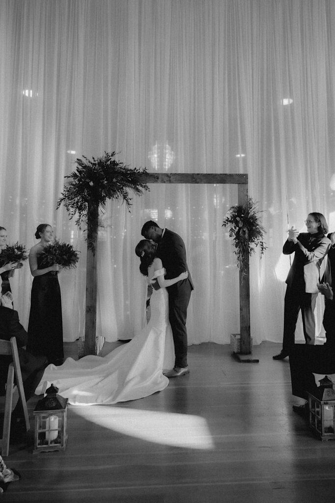 A bride and groom kiss after their wedding ceremony at the Artisans Building that was elegantly designed by Create a Scene in Springfield Illinois.