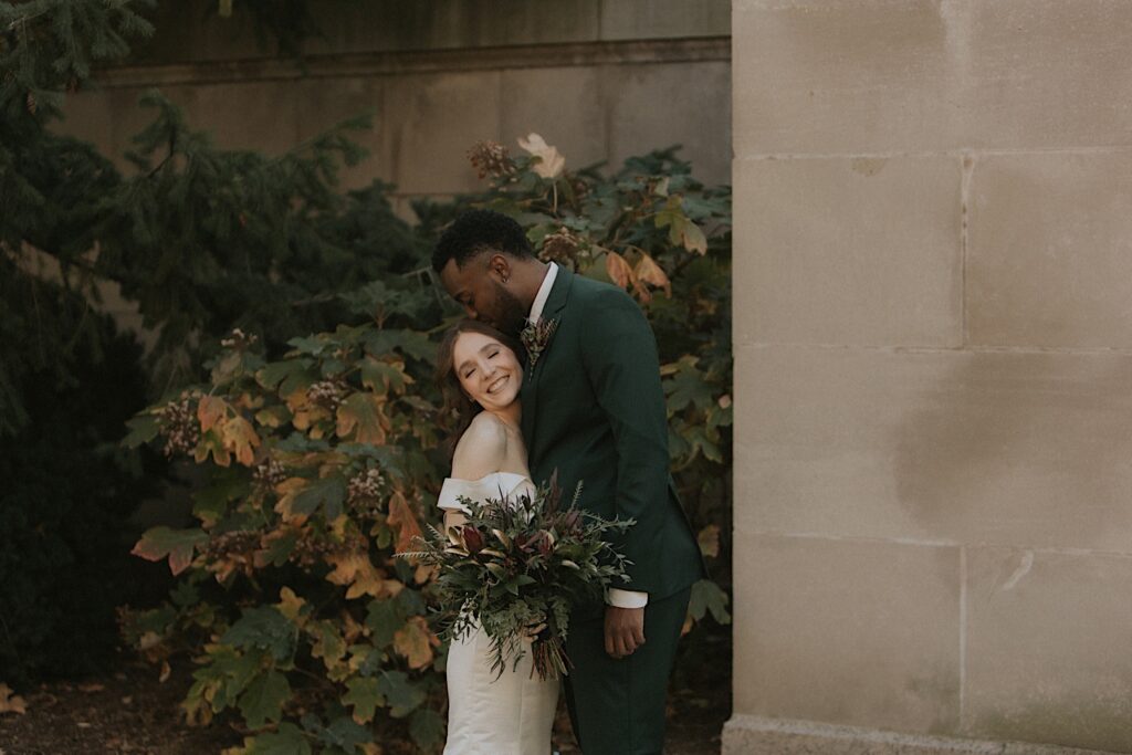 A groom kisses his bride on her temple after seeing her for the first time on their fall wedding day in Illinois.  