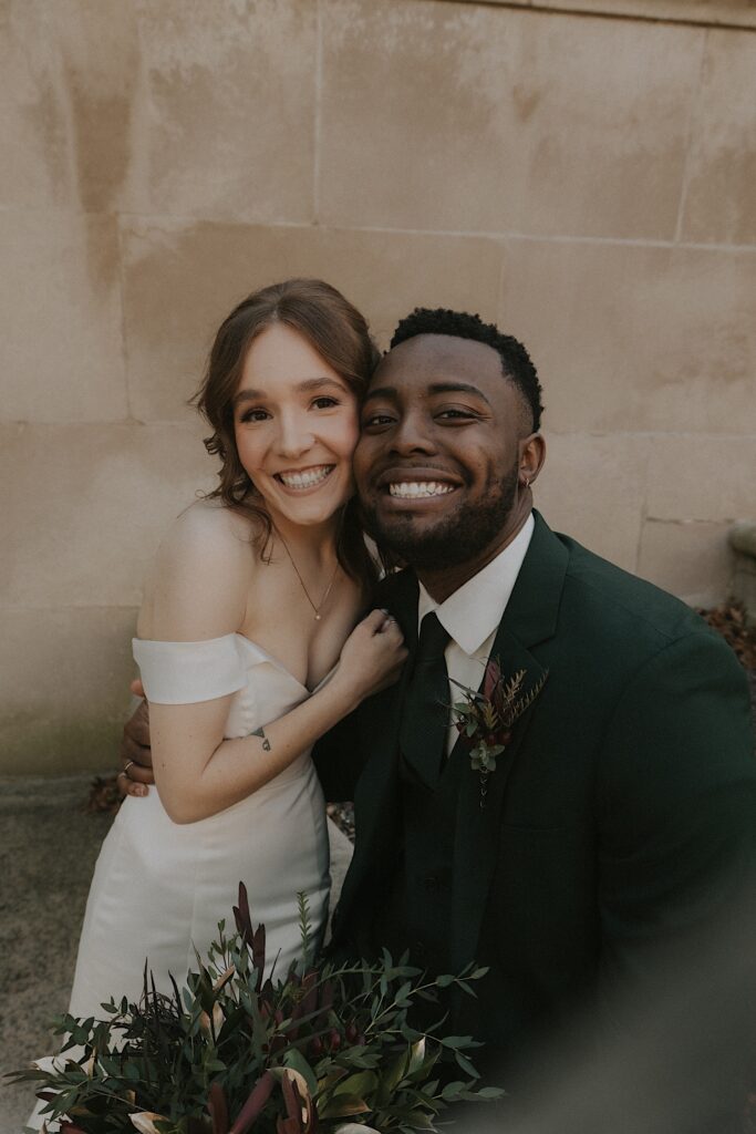 A bride and groom smile for a photo with their faces close together on the front steps of the Illinois State Capitol Building. 