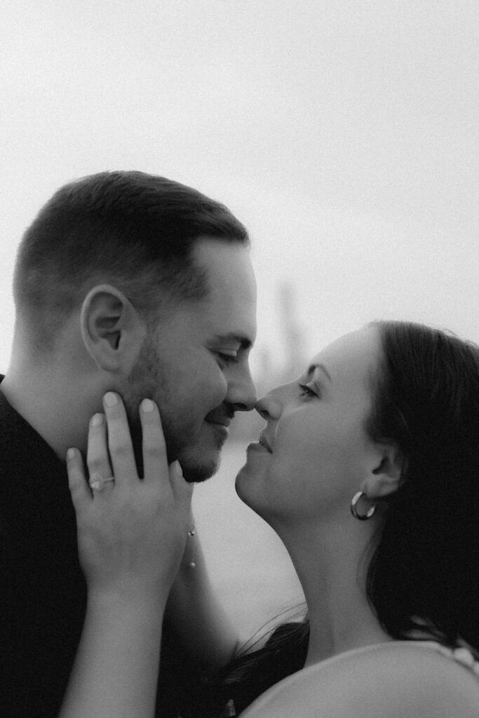 A bride and groom hold their faces together smiling at one another during their lake front engagement session in Chicago.  