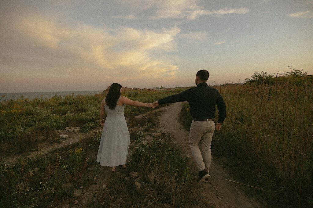 A bride and groom walk together holding hands north of the Planetarium in Chicago.  The sun is setting behind them. 