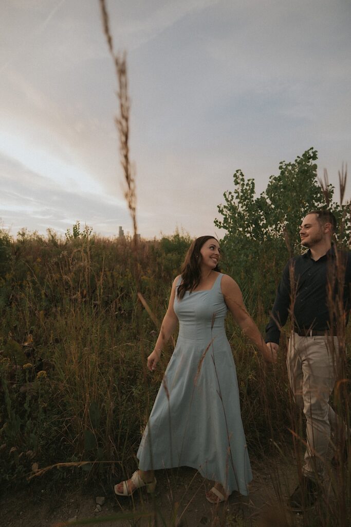 A bride walks holding hands with her fiancé during their engagement session in Chicago.  