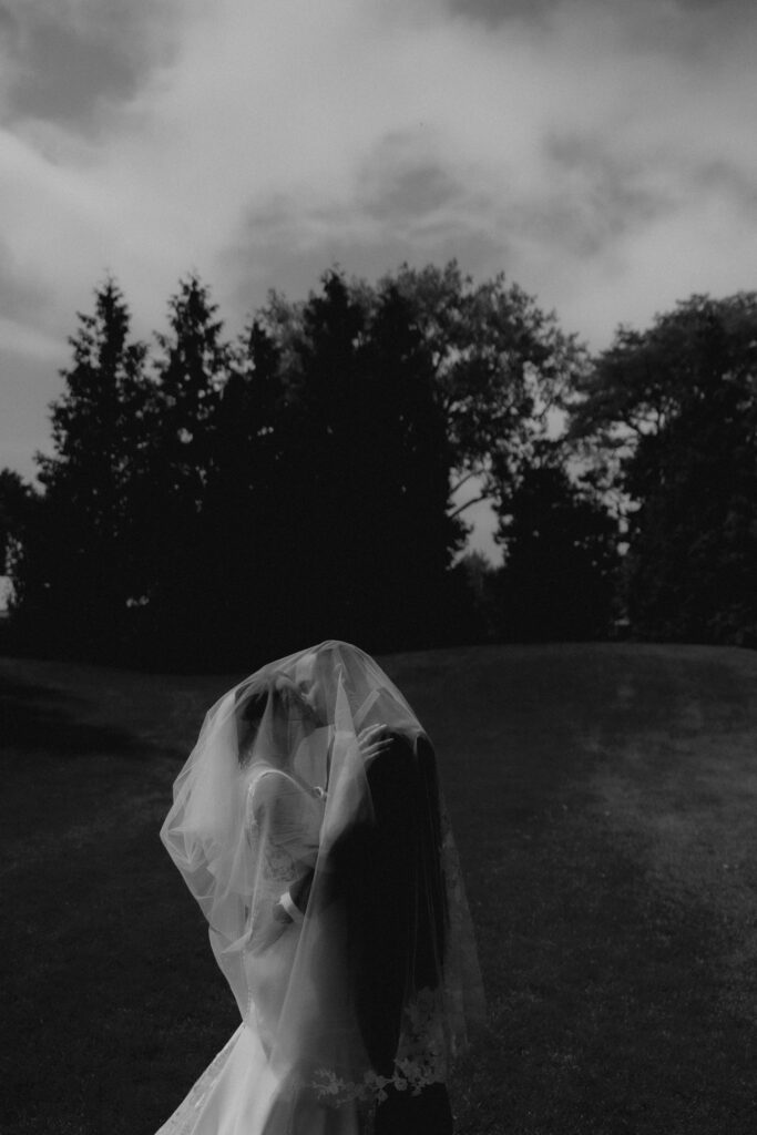 A bride and groom kiss under the brides veil at a country club during their Chicago suburbs wedding. 