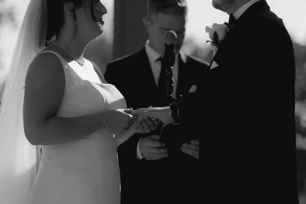 A bride and groom exchange wedding rings during their outdoor ceremony at their Chicago suburbs wedding venue. 