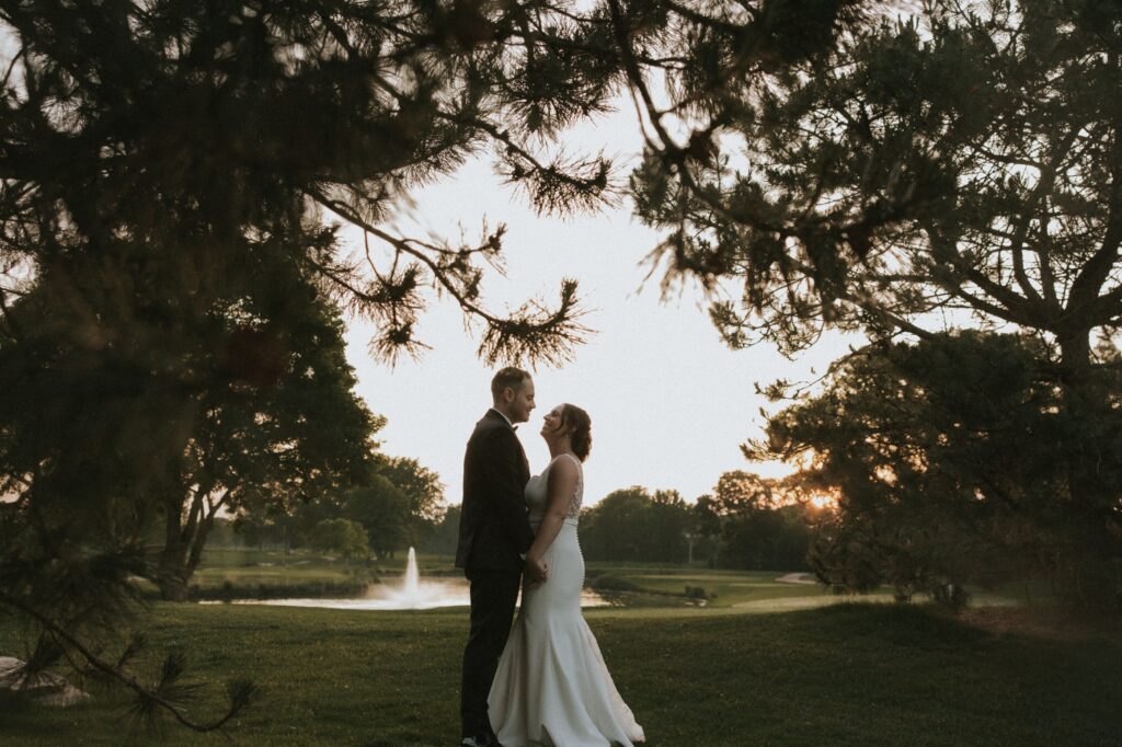 A bride and groom hold one another in front of a fountain on the golf course of their Chicago suburbs wedding venue the Chevy Chase Country Club. 