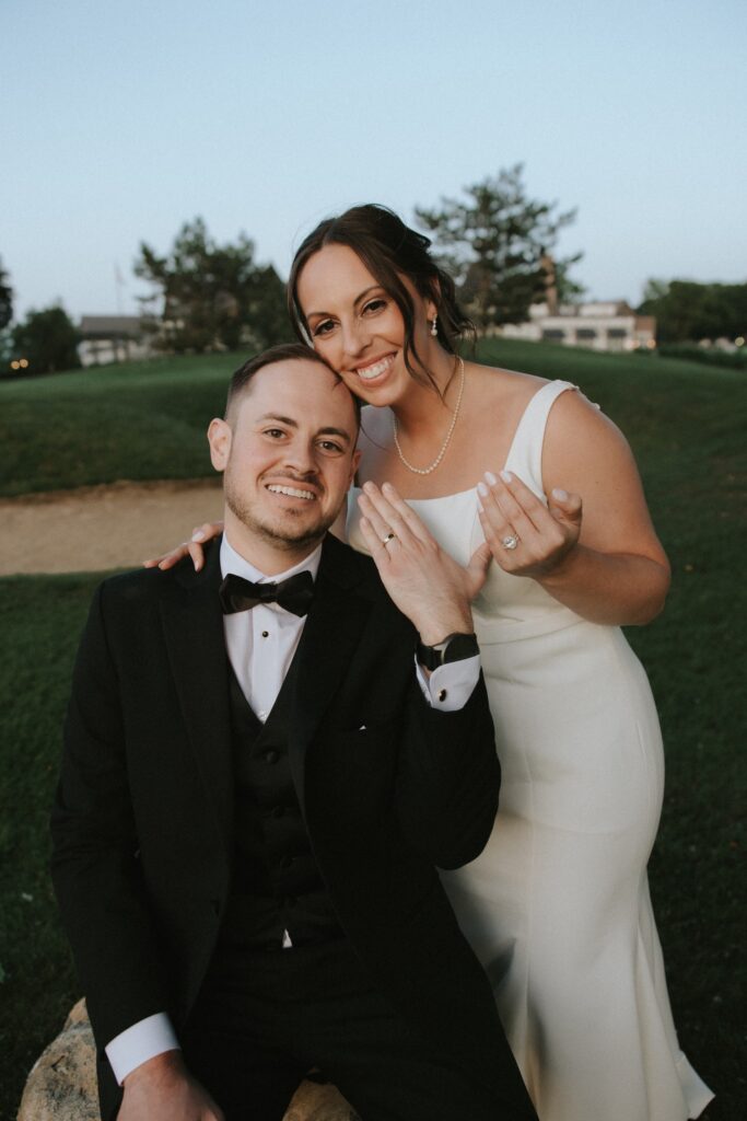 A bride and groom smile together showing off their wedding rings at their Chicago suburbs wedding at the Chevy Chase Country Club. 