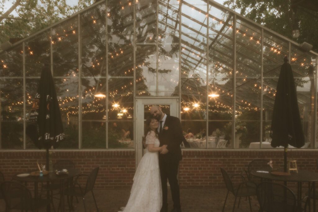 bride & groom stand in front of greenhouse at Silvercreek Restaurant in Urbana, Illinois